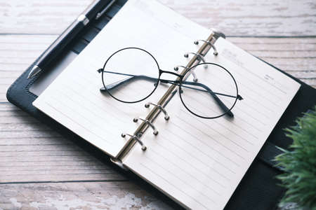 notepad, eyeglass and a pencil on wooden tableの写真素材