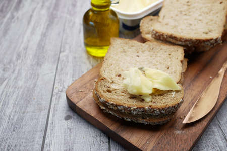 slice of butter and whole meal bread on chopping boardの写真素材