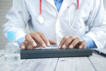 young male doctor typing on keyboard on desk ,の写真素材