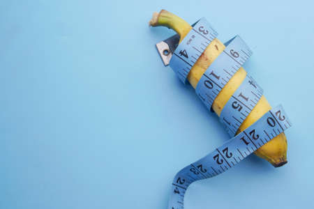close up of measurement tape and banana on blue backgroundの写真素材