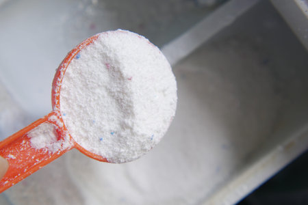 pouring Washing powder from a plastic spoon