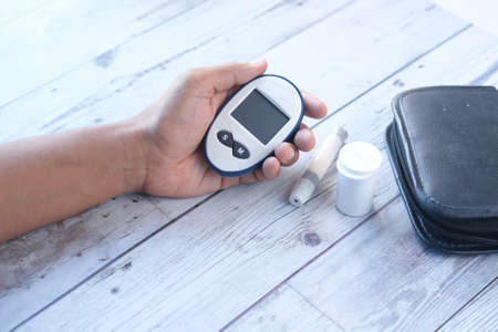 Rear view of hand hold a diabetic measurement tools on tableの写真素材