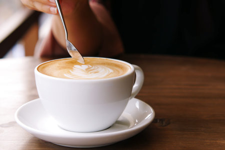 a cup of late coffee with flower shape design on top at cafe