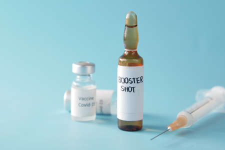 booster shot dose coronavirus vaccine and syringe on blueの写真素材