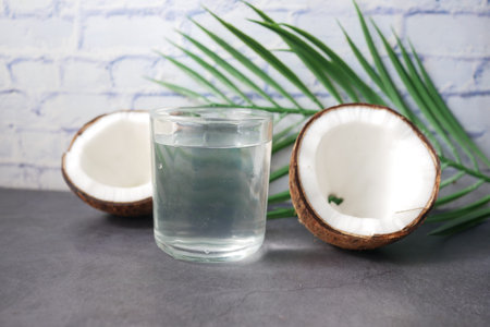 slice of fresh coconut and glass of coconut water on table