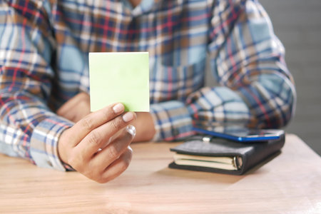 man hand hold a sticky note while sited