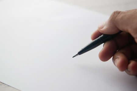 mans hand writing with pen on paperの写真素材