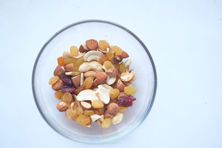 close up of many mixed nuts in a bowl on white