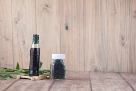 Black Cumin in a container with oil in a jar on table.の写真素材