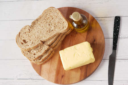 slice of butter and whole meal bread on chopping boardの写真素材