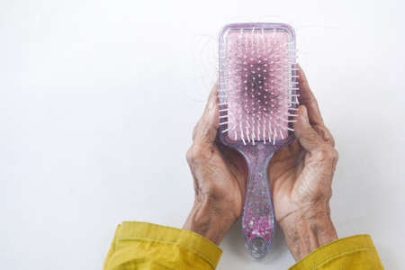 senior women hand hold a brush with lost hair on white backgroundの写真素材