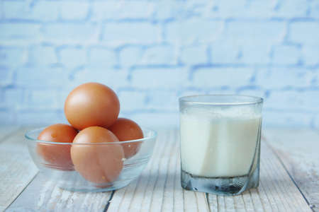 eggs in a bow and a glass of milk on tableの写真素材