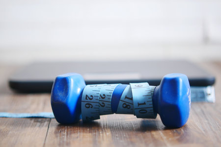 Fitness concept with dumbbell, measurement tape and weight scale on floorの写真素材