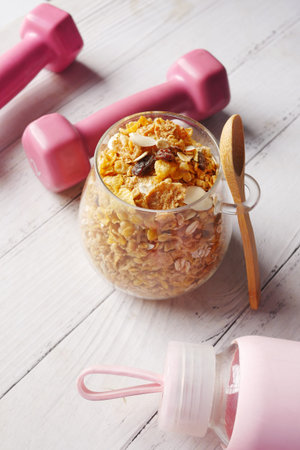 Home Made Musli in a bowl , dumbbell and water bottle on table