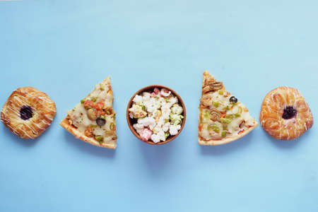 Slice of cheese pizza on a plate , donuts and popcorn on blueの写真素材