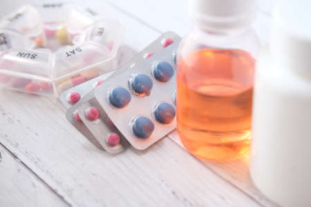 Close up of pills of blister pack, pill box and liquid container on tableの写真素材