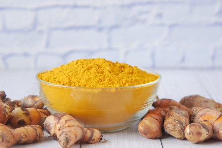 detail shot of turmeric root and powder in bowl on table ,