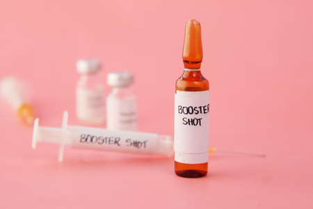 booster shot dose coronavirus vaccine and syringe on pinkの写真素材
