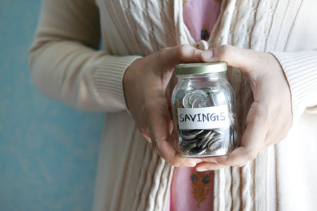 women hand hold a saving coins jar