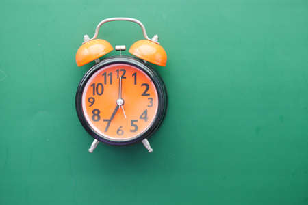 orange old alarm clock on green backgroundの写真素材