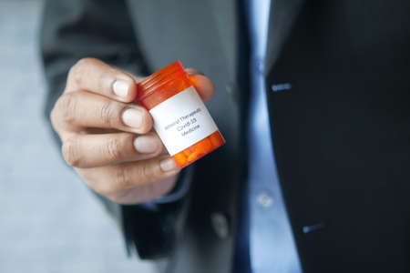 business man hand hold covid 19 medical medial pillsの写真素材