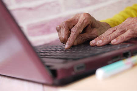 senior womens hand typing on laptop.の写真素材