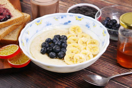 a bowl of oats, berry, banana and honey on table