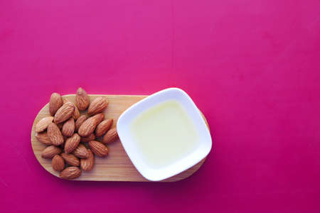 Almond oil in a container and almond nut on color background.の写真素材