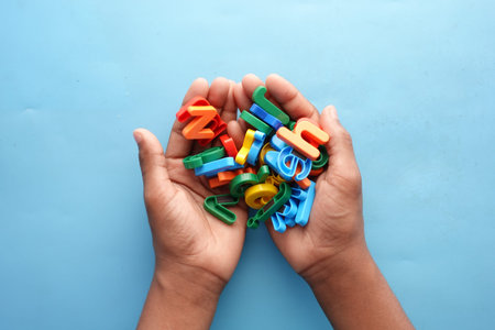 colorful plastic letters on childs hand on blue background