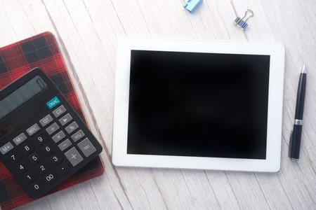 Flat composition of digital tablet and office stationary on black background