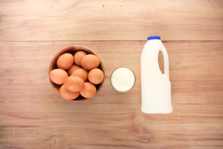 eggs in a bow and a glass of milk on tableの写真素材