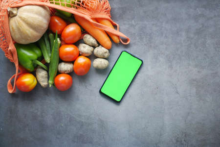top view of smart phone with fresh vegetable on tableの写真素材