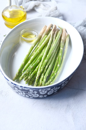 Asparagus green in a bowl with oil on tableの写真素材