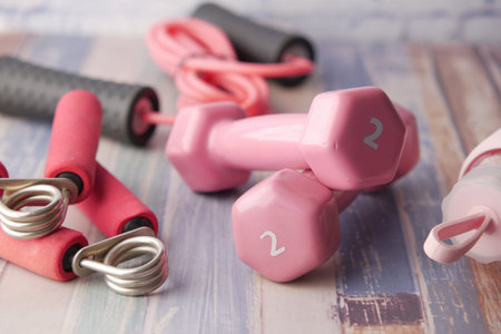 pink color dumbbell, shoe and headphone on pink background