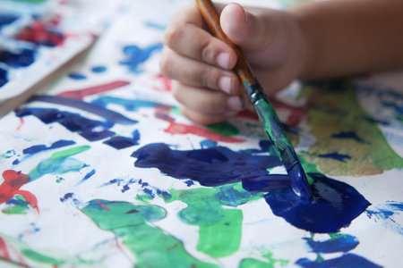 child hand drawing with art brush on a paperの写真素材