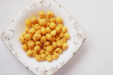 puffed corn rings chips in black bowl on white backgroundの写真素材