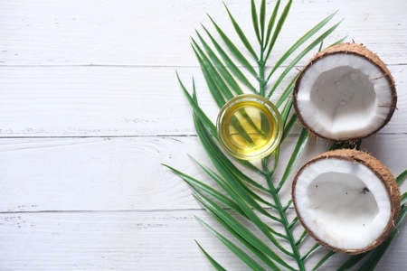 top view of slice of fresh coconut and bottle of oil on a tableの写真素材