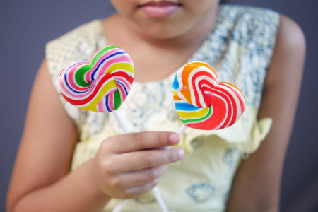 child girl hand hold rainbow heart shape candy