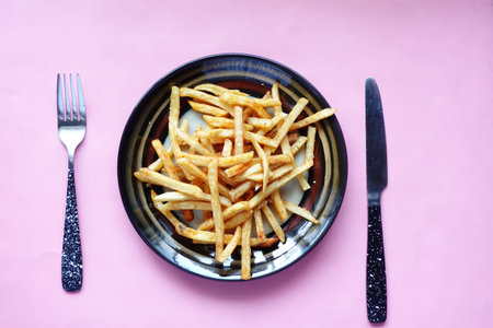 top view of french fries on a plate with cutlery on table