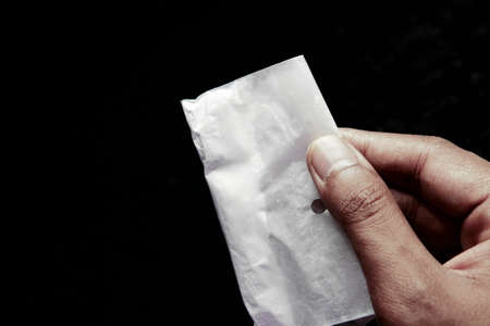 drug addiction concept with hand holding heroine packet on black backgrundの写真素材