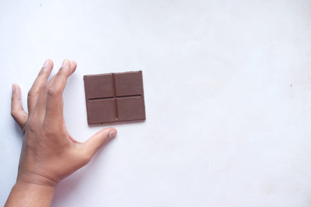 hand pick dark chocolate on a plate on table close up