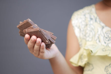 child girl hand pick dark chocolate against gray backgroundの写真素材