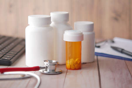 doctors workplace with container, keyboard and prescription on desk.の写真素材