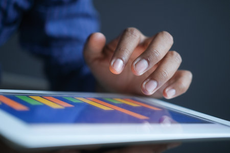 mans hand working on digital tablet at office desk, using self created chartの写真素材