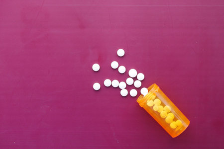 white color medical pills spilling on pink