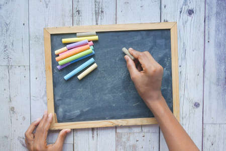 child hand drawing with colorful chalk on a chalkboard on black backgroundの写真素材