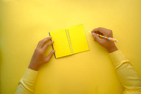 man hand writing on notepad on yellow backgroundの写真素材