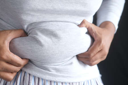 mans hand holding excessive belly fat, overweight conceptの写真素材