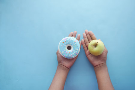 hand holding donuts and apple on hand on blue backgroundの写真素材