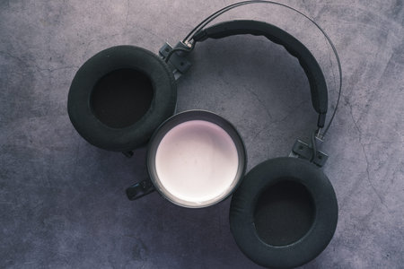 coffee and wireless headphones on black background